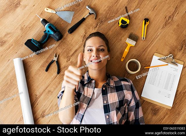 woman with working tools lying on wooden floor