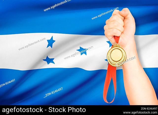 Sportsman holding gold medal with flag on background - Republic of Honduras