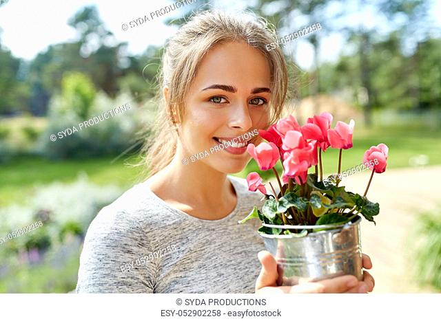young woman with cyclamen flowers at summer garden