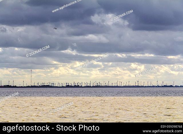 dramatic illuminated coastal scenery including a distant wind farm near Neuharlingersiel in Eastern Frisia, Germany