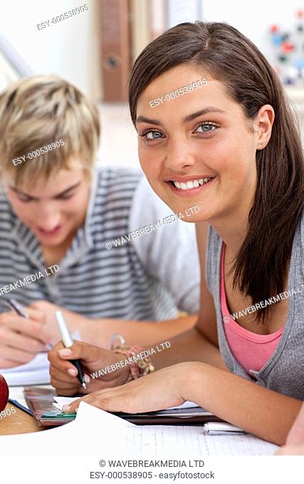 Smiling teen girl studying in the library with her friends Concept of education