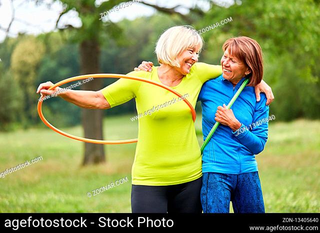 Zwei Senior Frauen machen zusammen Gymnastik mit dem Reifen im Park