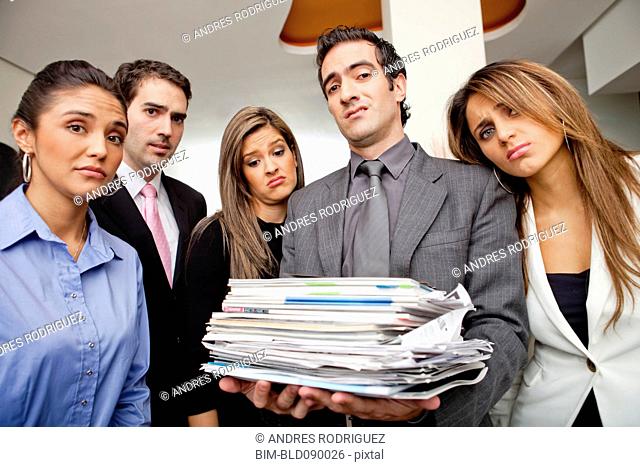 Frustrated Hispanic business people with pile of paperwork