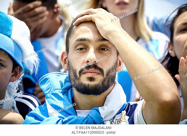 Argentinian football fan holding hand on head in disappointment at match