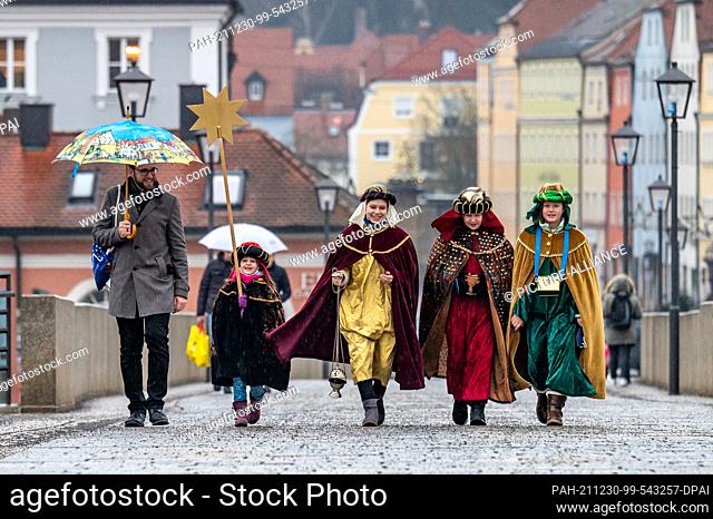 30 December 2021, Bavaria, Regensburg: Carolers walk across the Stone Bridge. The nationwide carol singing campaign opened this year in Regensburg