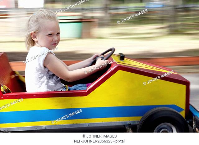 Blond girl riding toy car