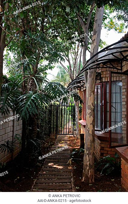 Back garden path between wall and house within residence, Moreleta Park, Pretoria, Gauteng Province, South Africa