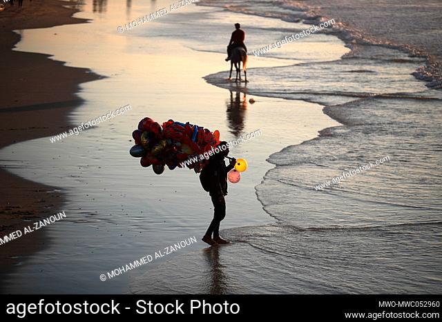 A Palestinian man sells balloons to children on the Gaza City beach. Gaza City. Palestine