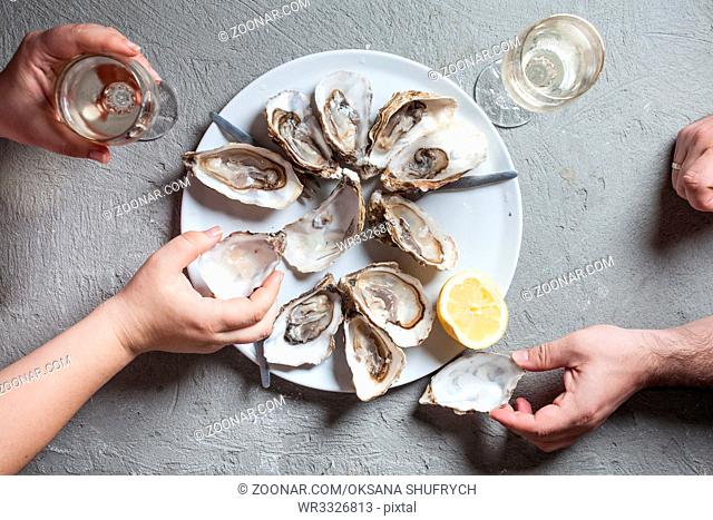 Delicious oysters with slice of lemon and glasses of white wine, top view