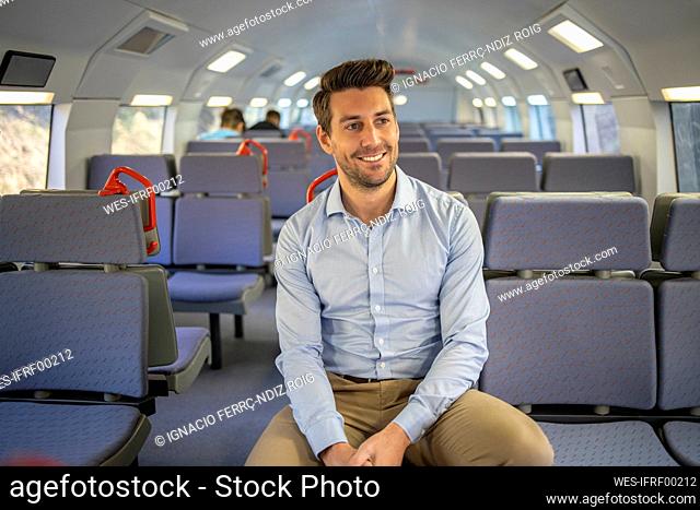 Smiling businessman looking away while sitting in train