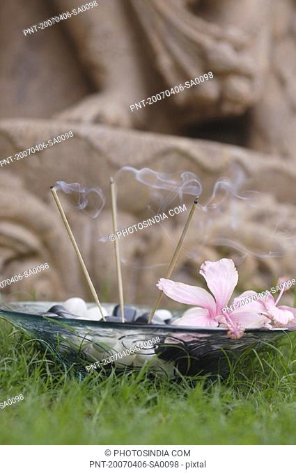 Close-up of burning incense sticks with pebbles in a glass bowl