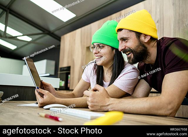 Happy business couple using digital tablet at desk in modern office