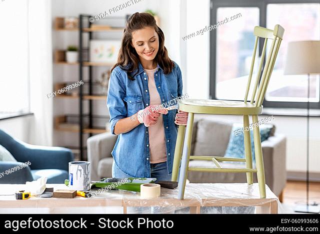 woman painting old chair in grey color at home