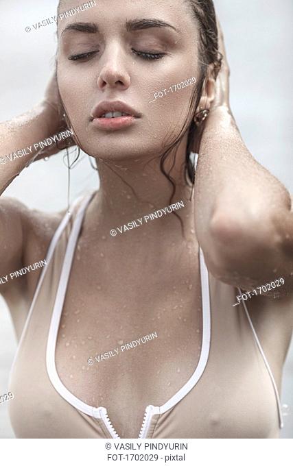 Close-up of sensuous young woman with closed eyes touching wet hair