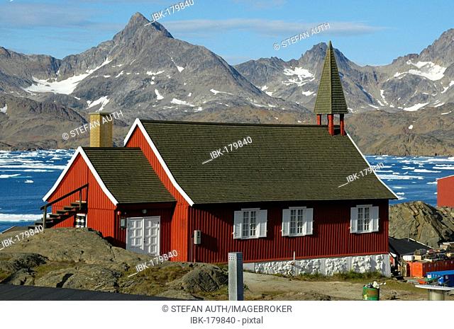 Red church at fjord and mountain chain Ammassalik Eastgreenland