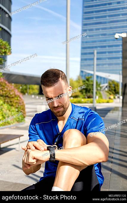Young sportsman checking time on wristwatch