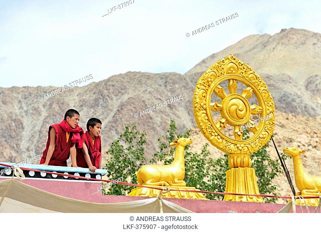 Novices looking from rooftop with wheel of life, monastery festival, Phyang, Leh, valley of Indus, Ladakh, Jammu and Kashmir, India