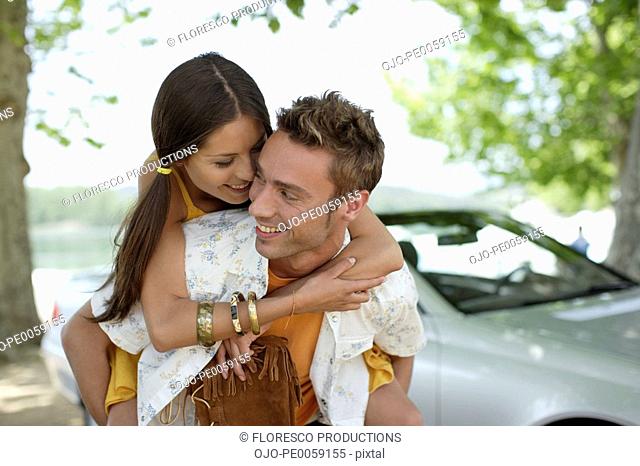 Couple outdoors by convertible car embracing
