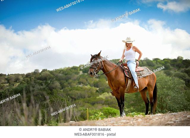 USA, Texas Hill Country, cowgirl sitting on horse