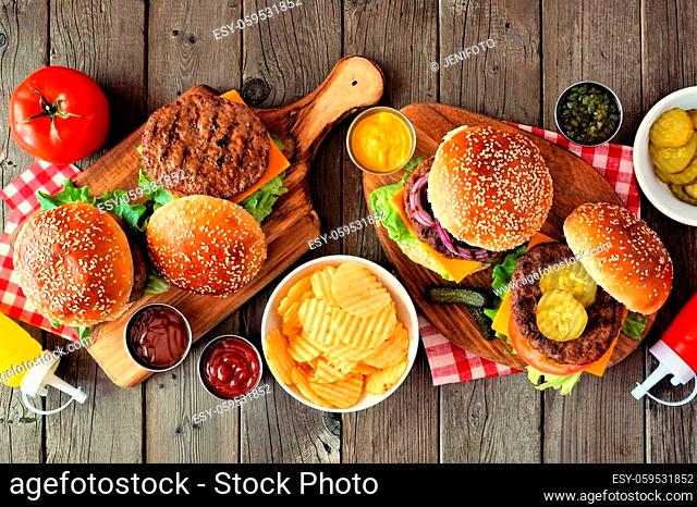 BBQ hamburger table scene. Top view over a dark wood background