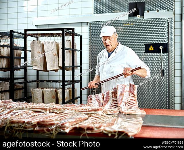Butcher wearing cap arranging raw meat in factory