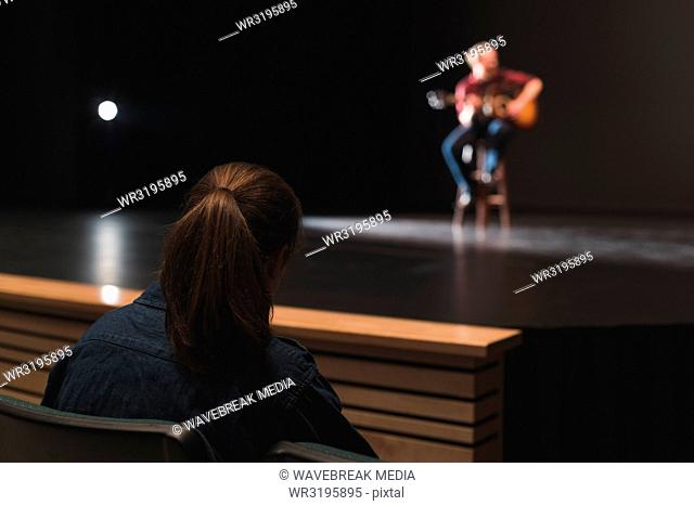 Woman looking at musician playing guitar on stage