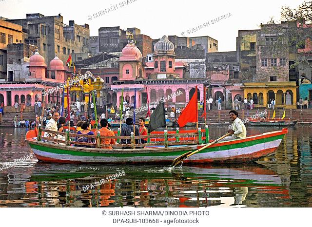 Pilgrims in boat in front of colorful temples on banks of Yamuna river , Vishram Ghat , Mathura , Uttar Pradesh , India