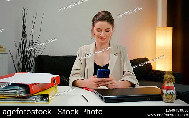Woman using smartphone after a successful day's work. Chat with a friend and smile