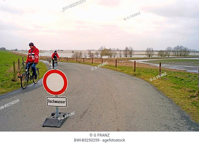 traffic sign with high water warning and passage only for residentsplaced in the middle of an asphalt road leading to the floodplains at the river Weser at...