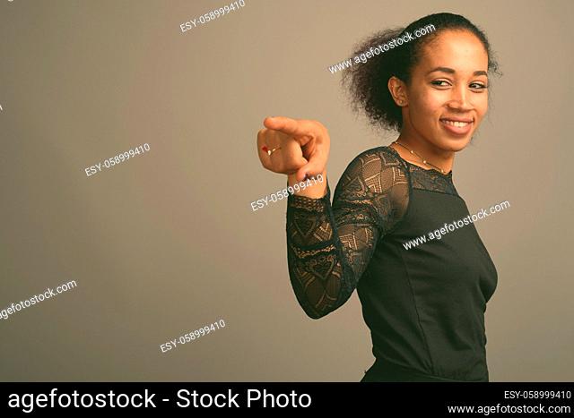 Studio shot of young beautiful African woman against gray background