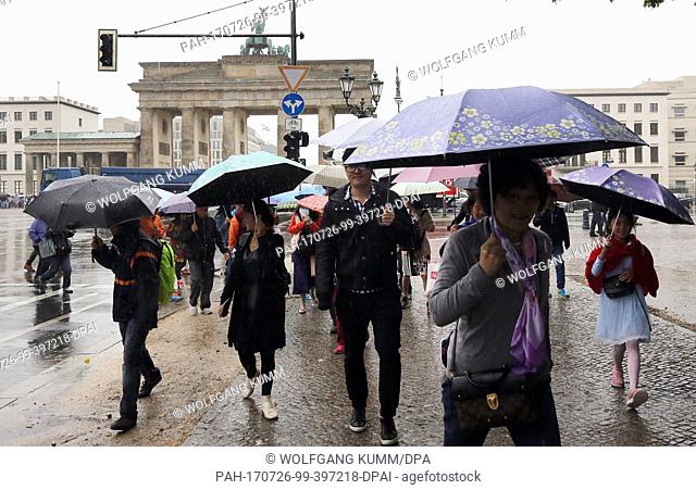 Tourists walk by the Brandeburg Gate under pouring rain and temperatures of 16 degreees Celsius in Berlin, Germany, 26 July 2017
