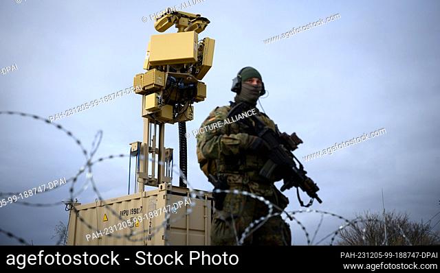 05 December 2023, Romania, Constanta: A Bundeswehr soldier stands in front of a defense system against small unmanned aerial vehicles (ASUL) to protect the...