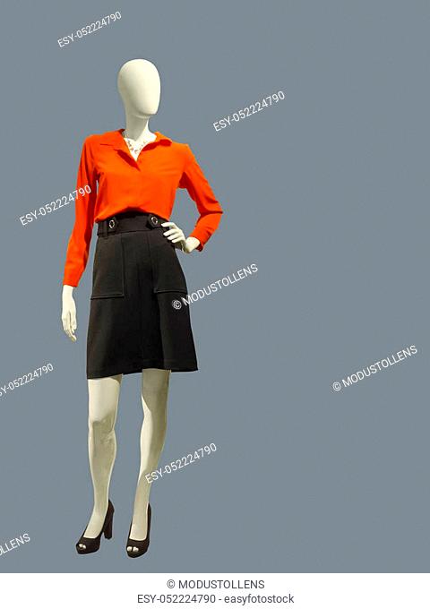 Full length female mannequin dressed in red blouse and black skirt over gray background. No brand names or copyright objects