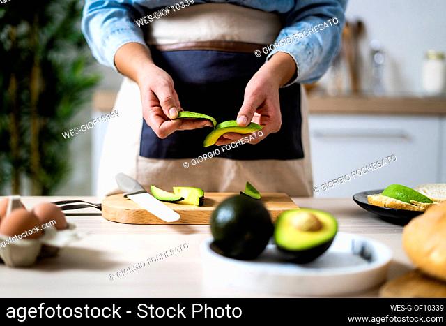 Mid section of woman peeling avocados
