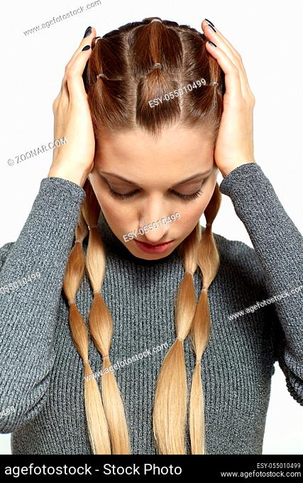 Portrait of beautiful young dark blonde woman. Female with creative braid hairdo on gray background. Girl with hands on head