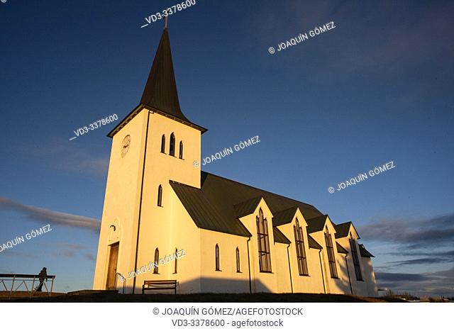 View of the church, illuminated by the sunset sun, from Borgarnes, (near Reykjavik) in Iceland. A sample of the typical traditional architecture of the...