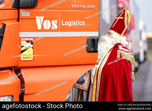 05 December 2021, Rhineland-Palatinate, Worms: Michael Hommer, deacon in the diocese of Trier, dressed as St. Nicholas, distributes gift bags to parked trucks...