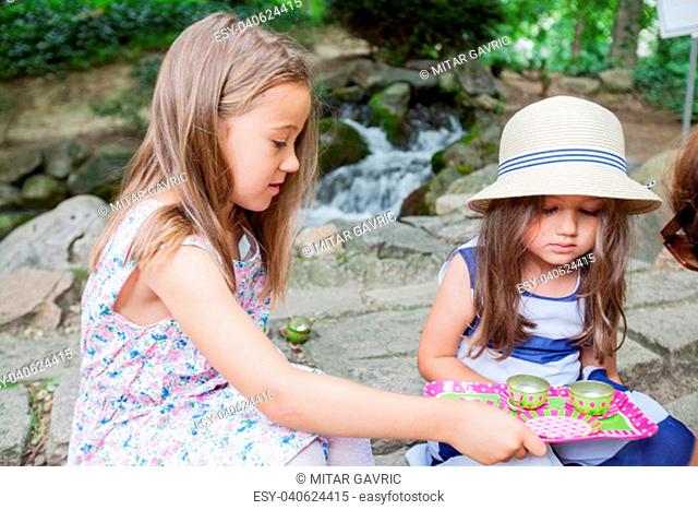 Two little girls at picnic in park, playing in nature