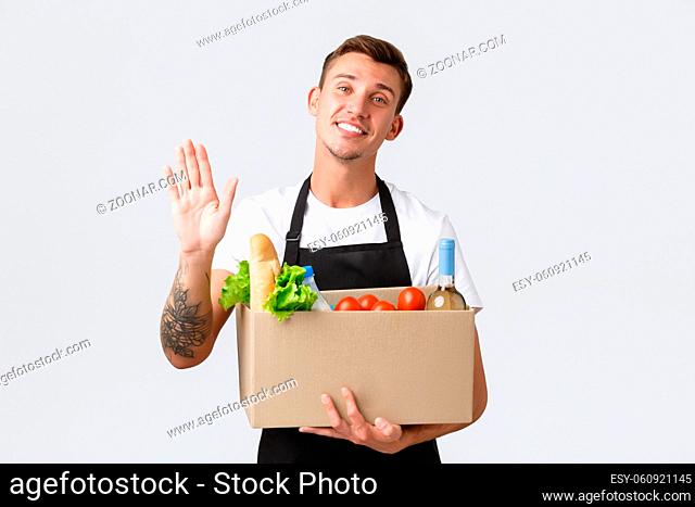 Retail, grocery shopping and delivery concept. Friendly handsome salesman made box with groceries, delivering food order