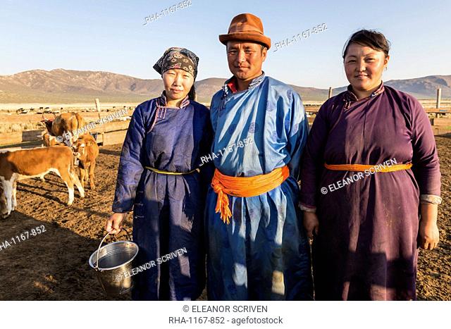Smiling nomadic people in traditional clothes (deels) in milking pen at daw in summer, Nomad camp, Gurvanbulag, Bulgan, Mongolia, Central Asia, Asia