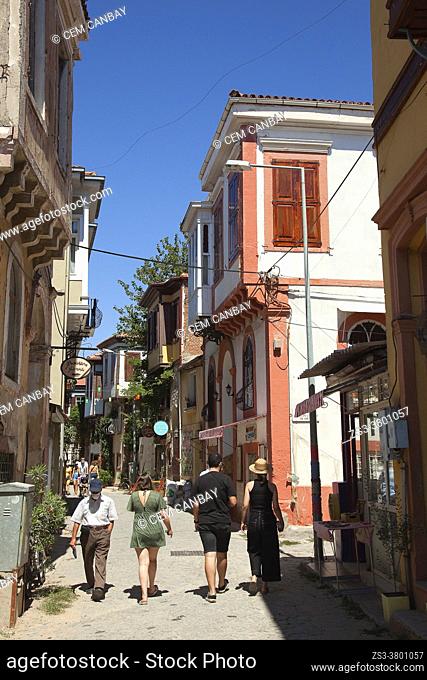Tourists walking in the street in front of the traditional Turkish houses at Macaron district in the town center of the ancient Aeolian port-town called...