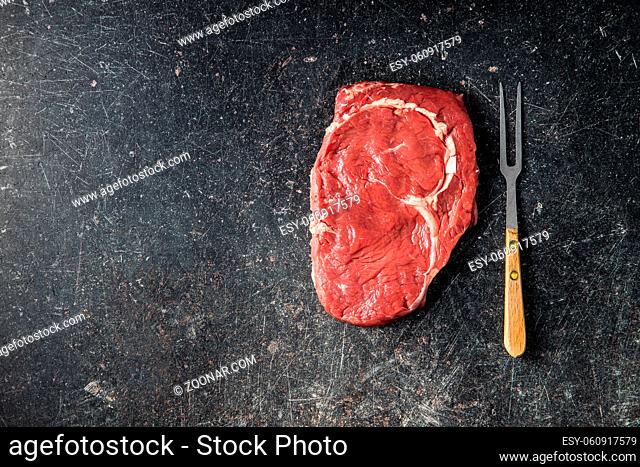 Sliced raw ribeye steak on a black kitchen table. Top view