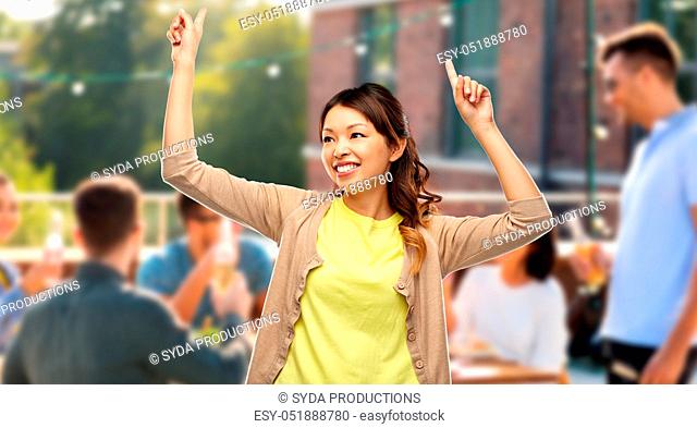 happy asian woman dancing over rooftop party