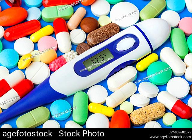 Pills and electronic thermometer (37.5 degrees) - abstract medical background