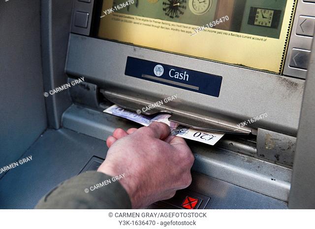 Detail of a hand withdrawing money from a cash machine