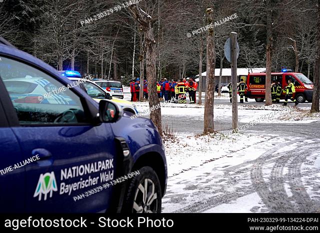 29 March 2023, Bavaria, Neuschönau: A Bavarian Forest National Park vehicle and fire department emergency personnel stand near the site where a small plane...
