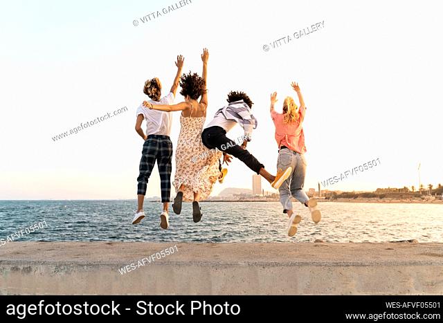 Carefree friends jumping on a quay wall
