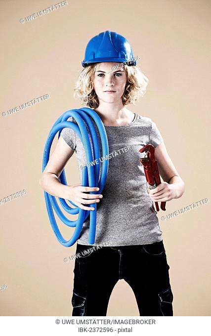 Girl wearing a hard hat and holding a pipe wrench