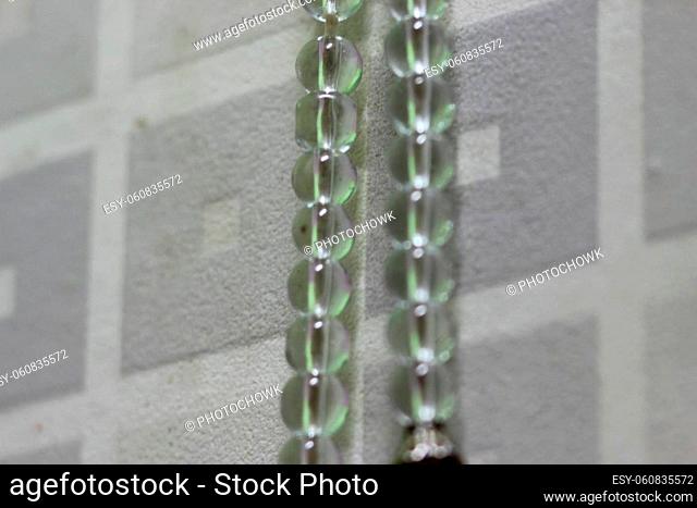 Macro photograph with selective focus of glass shiny prayer beads or rosary with copy space for text. Religion concept of ramadan or Eid for muslims