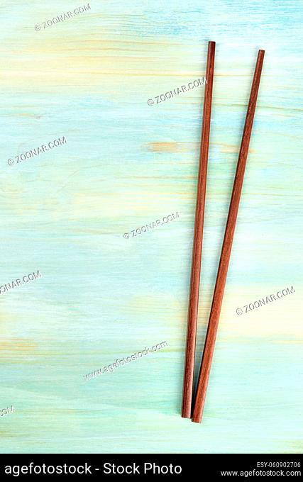 A pair of chopsticks on a teal blue background with copy space